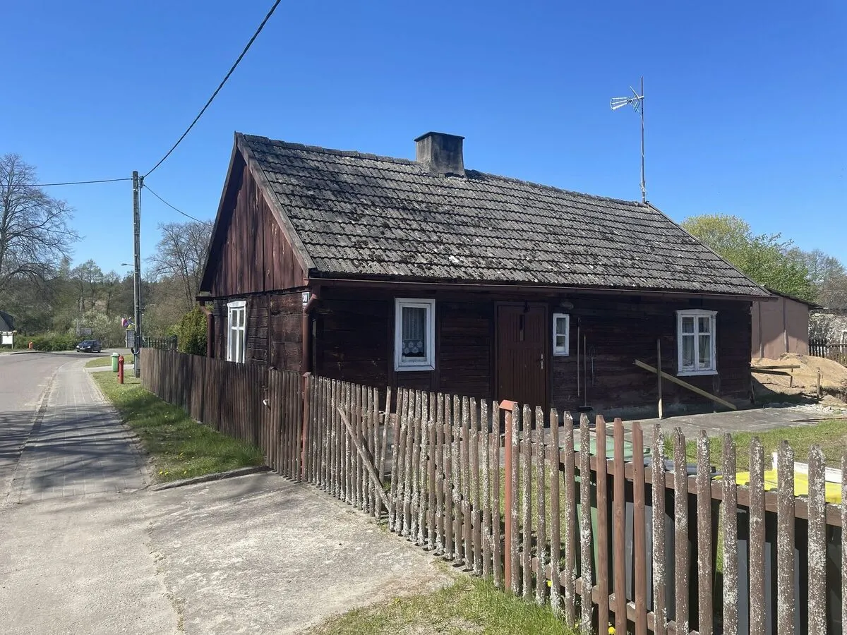 Stara drewniana chata za sztachetowym płotem przy drodze w Borsku