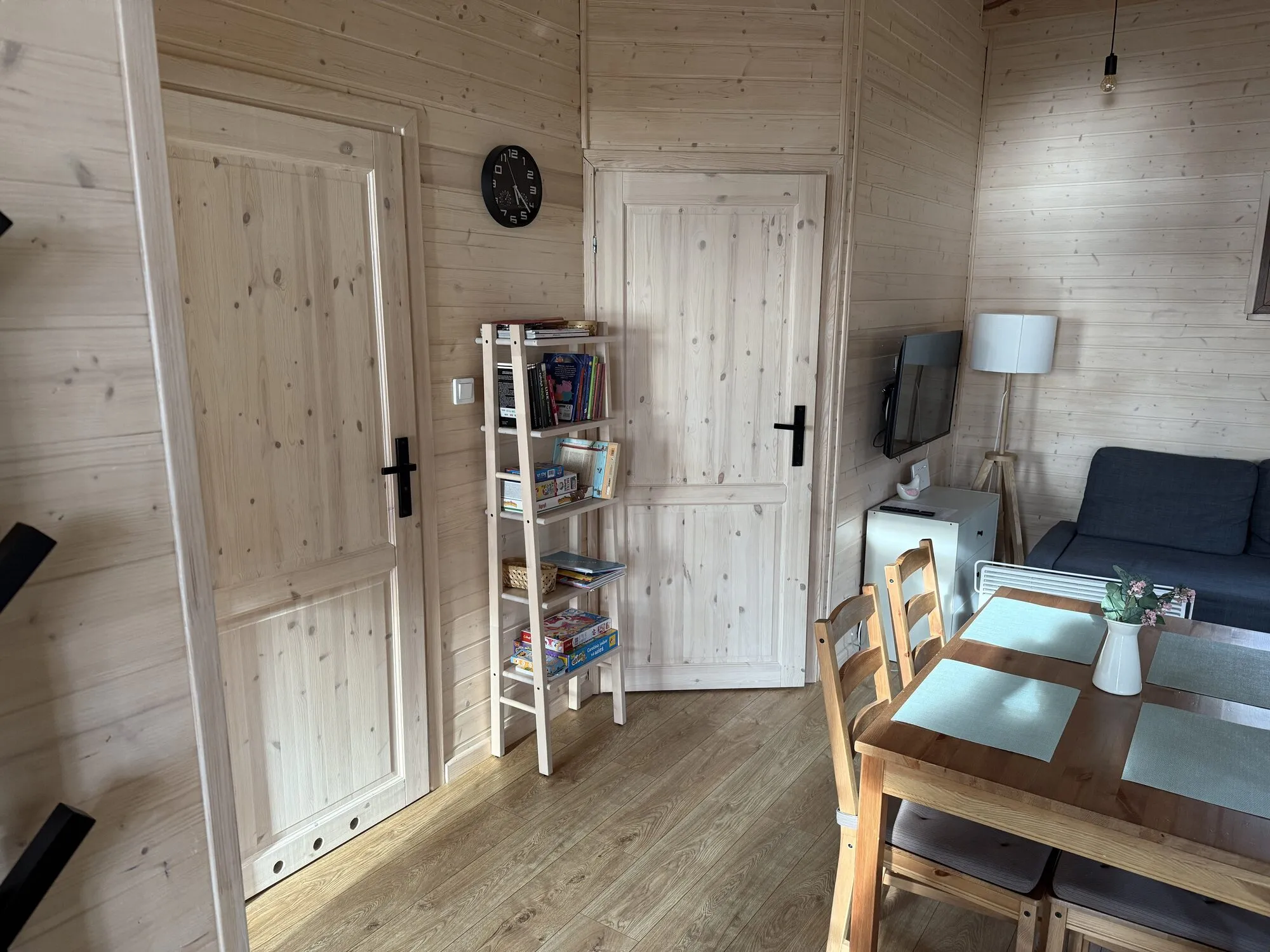 Living room with dining area, bookshelf and corner sofa in the Forest cabin