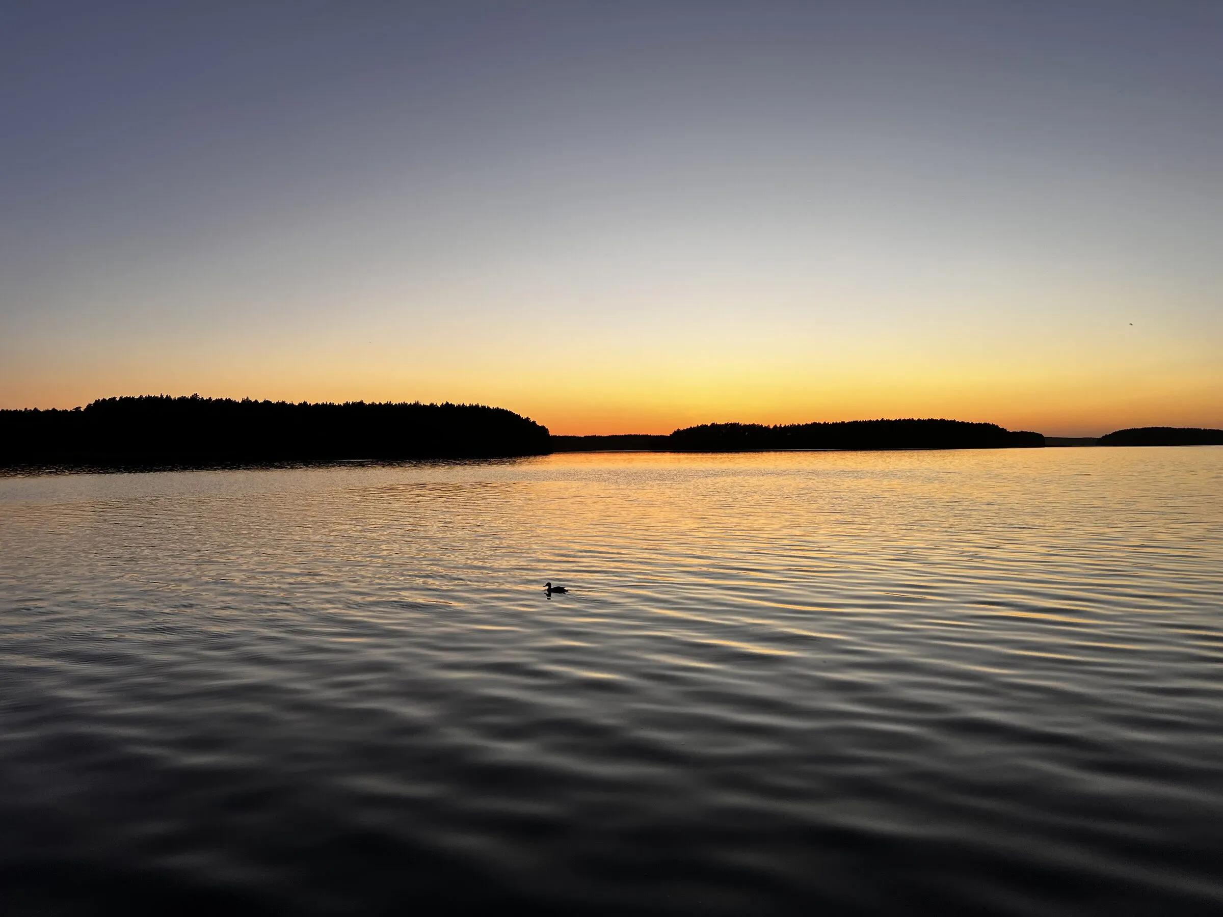 Sonnenuntergang am Wdzydze-See in Borsk, ruhiges Wasser und bewaldete Inseln