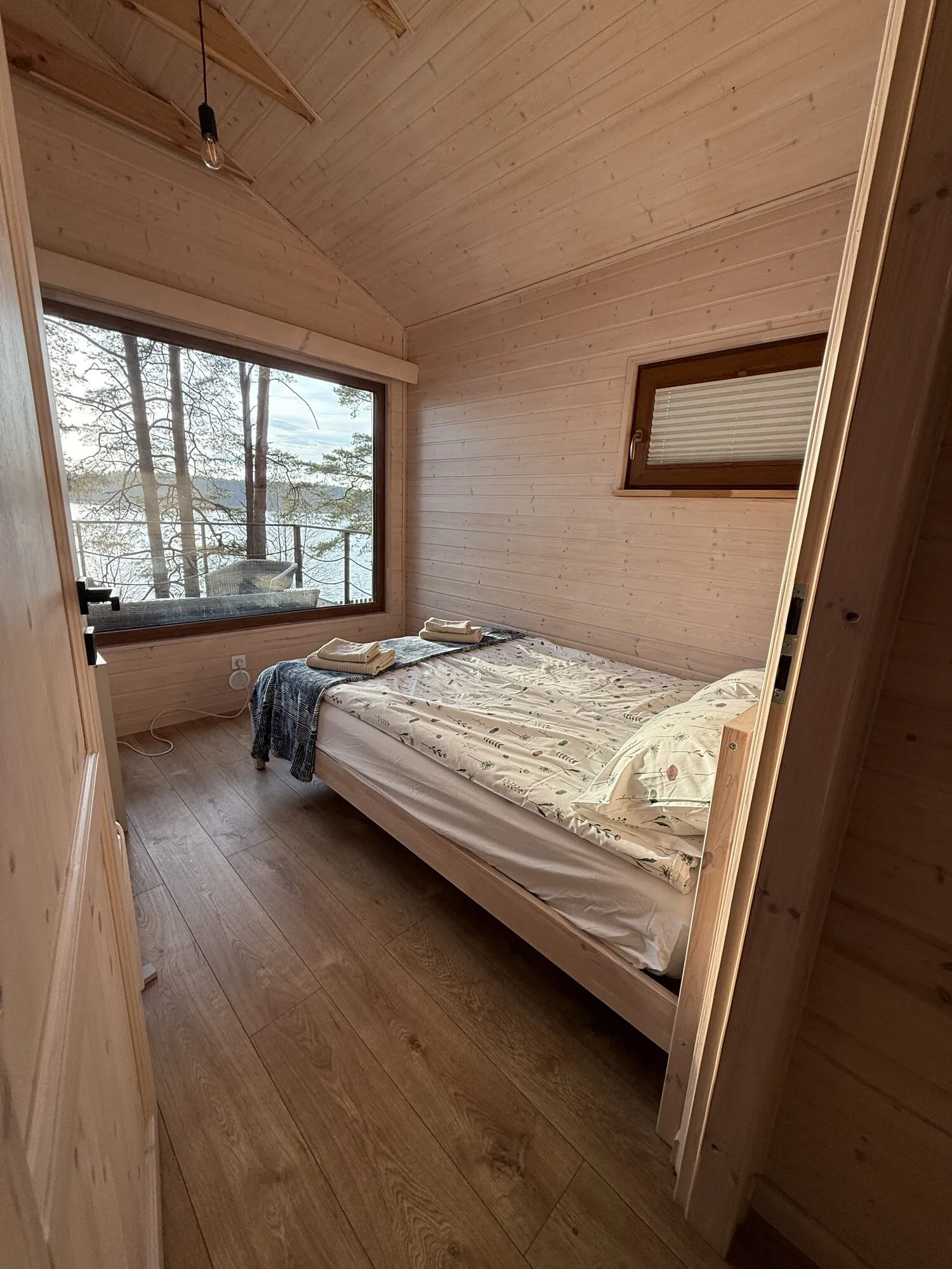 Double bed in the Panorama cabin bedroom, pines and Lake Wdzydze outside the window