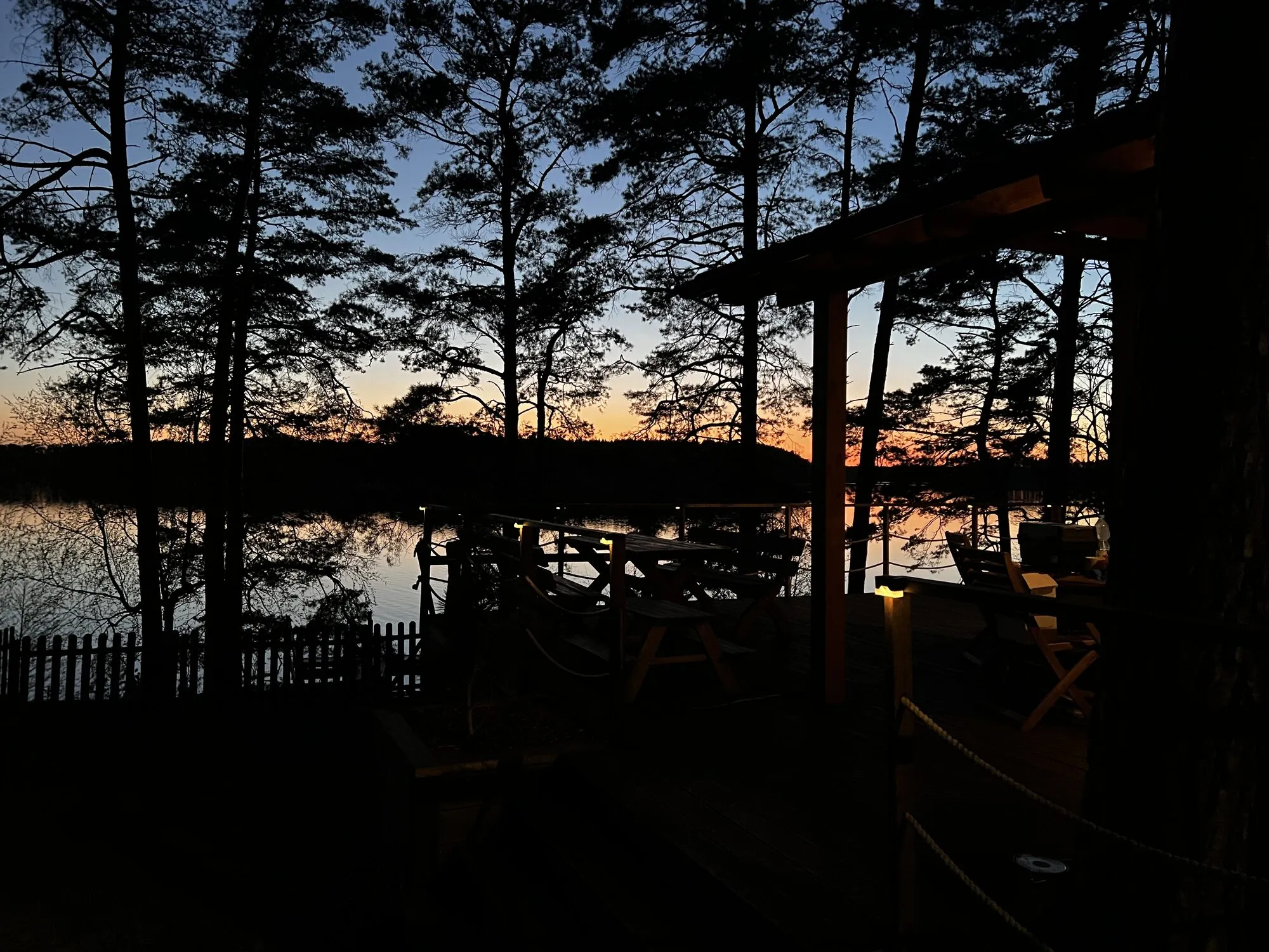 Evening on the Panorama cabin terrace, pine silhouettes and the lake after sunset