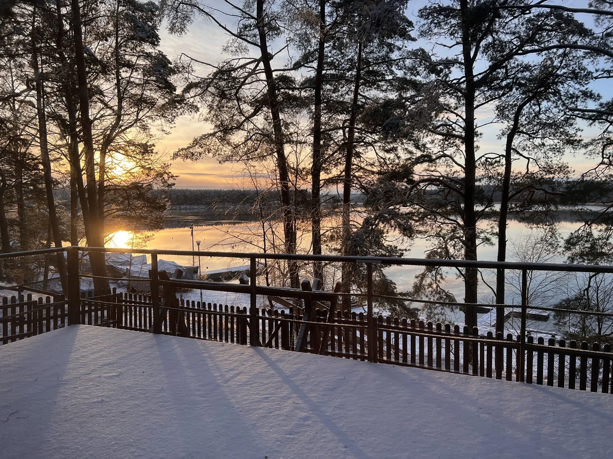 Panorama cabin terrace in winter at sunset over Lake Wdzydze