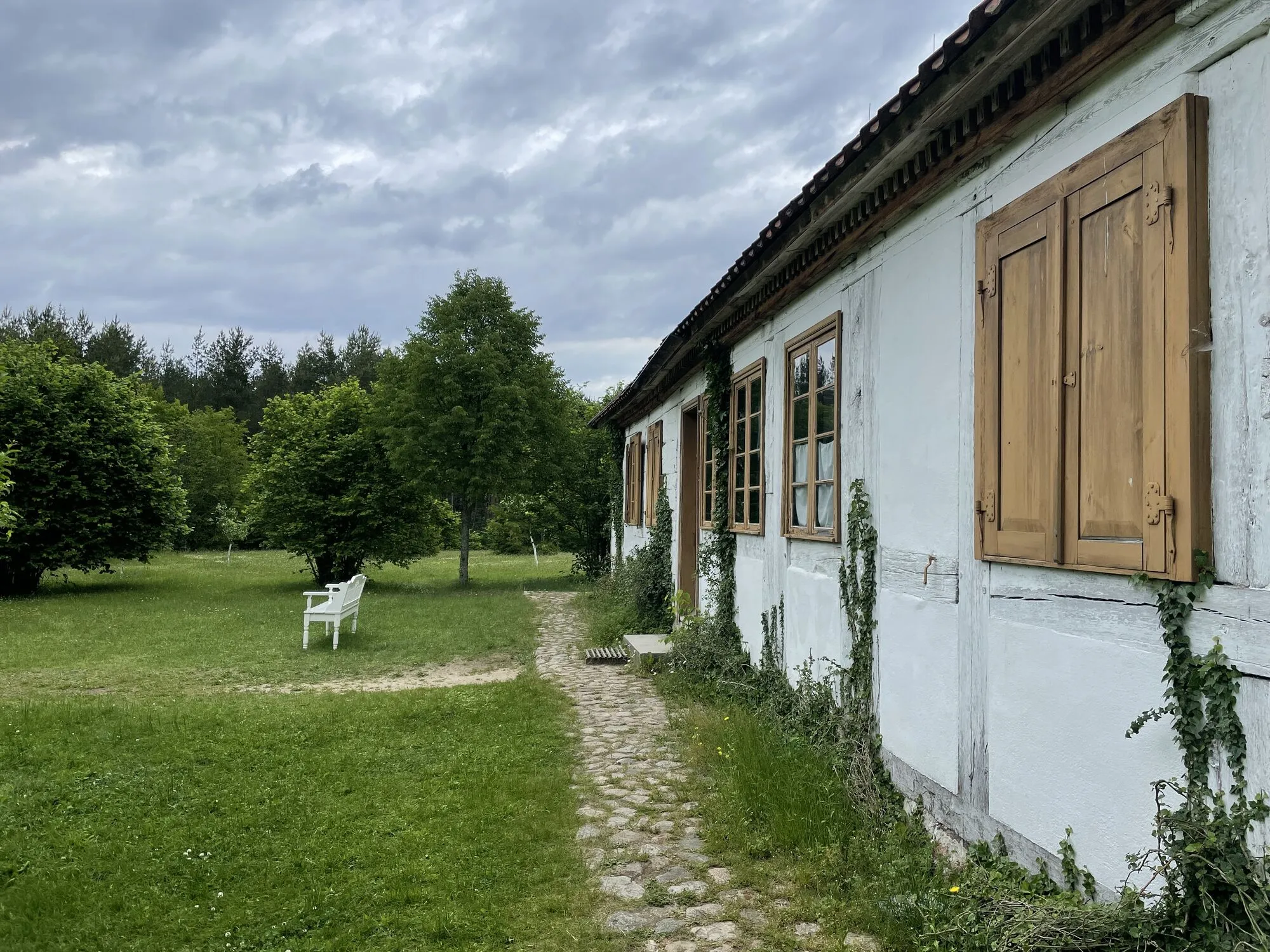 Bielona chata z drewnianymi okiennicami i łąka w skansenie we Wdzydzach Kiszewskich