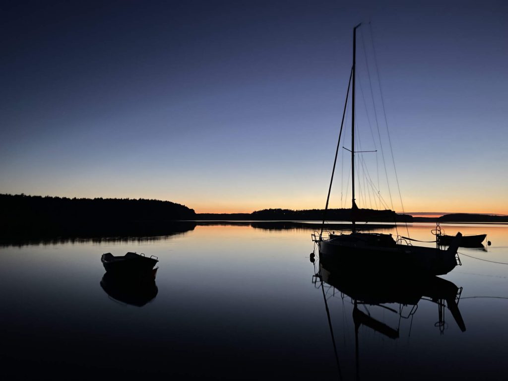 Domki Borsk - widok z brzegu jeziora na zachód słońca i łodzie.